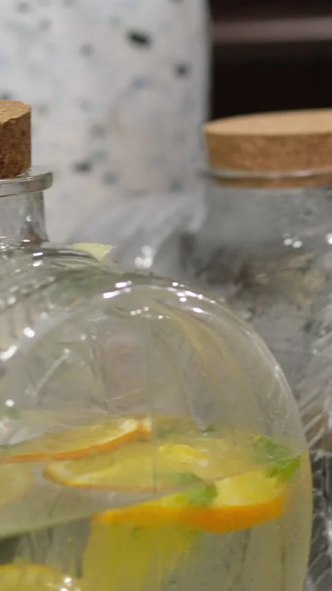 Large transparent jar of orange lemonade on a table outside Stock Footage 310490500