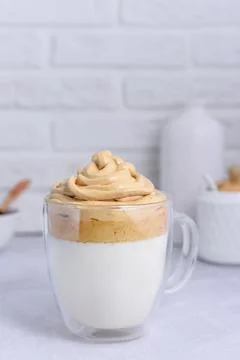 Large transparent mug with Dalgona coffee on a light background. Fotos de archivo