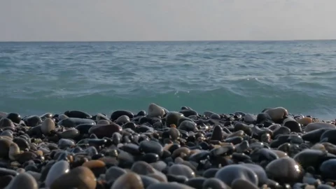 Large transparent waves with foam. Sea pebble beach with colorful stones Видео 80073100