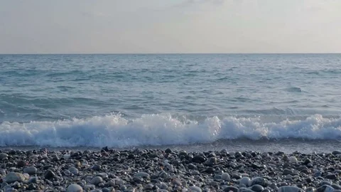 Large transparent waves with foam. Sea pebble beach with colorful stones. Stock Footage 80245173