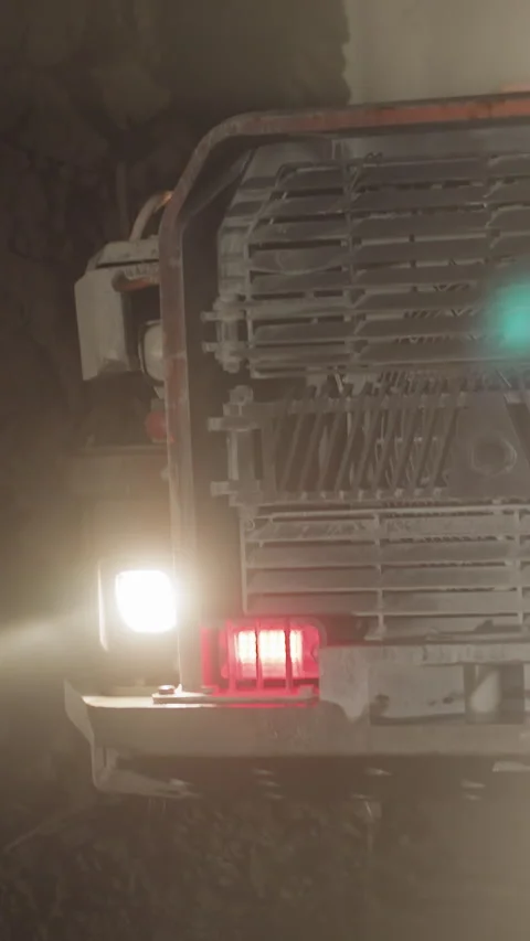Large transport moves in ore mine illuminating dark area Stock Footage 309049994