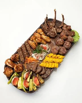 Large tray of mixed grilled meat and vegetables isolated on white background Stock Photos