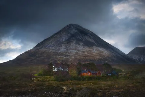 Large triangular shaped mountain in Glen Sligachan with typical wooden huts o Stock Photos