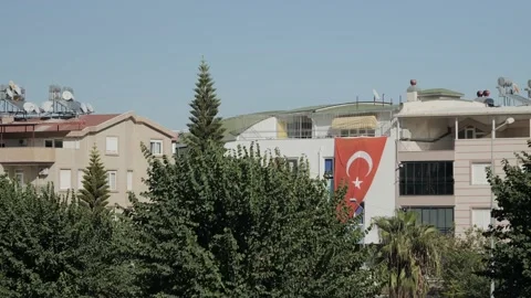 A large Turkish flag is flying on the house on a sunny warm day Stock Footage 220132921