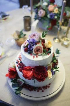 A large two-tiered cake decorated with fruit and fresh flowers. Stock Photos