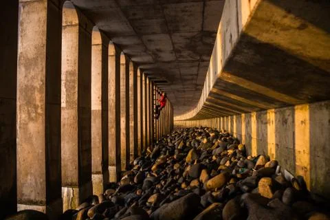Large underground bridge structure on beach in Japan. A man climbs a ladder o Foto stock