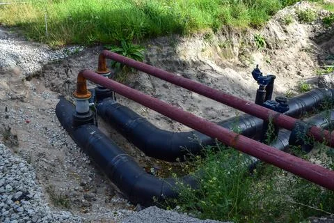 Large underground heating pipes in deep excavated trench Stock Photos