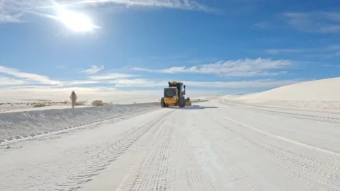 Large unmarked grader smoothing out white sand road in the desert isolated a Vídeo Stock 147256789