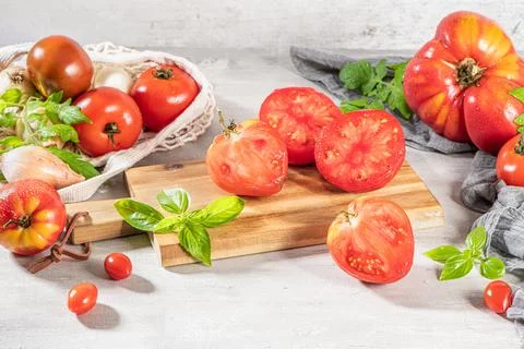 Large variety of tomatoes on rustic kitchen counter. Preparation of tomato sa Stock Photos