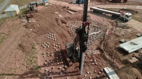 A large vertical pile-driving crane hammers reinforced concrete piles into the Video stock 165915697