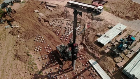 A large vertical pile-driving crane hammers reinforced concrete piles into the Stock Footage 194676647