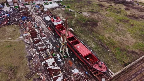 Large vessel under repair at shipyard with crane and materials Vidéo 337941624