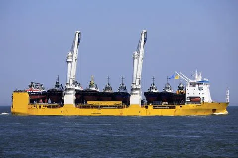 A large vessel with unique lifting capabilities carrying multiple tugboats Stock Photos
