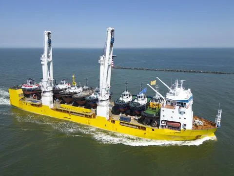 A large vessel with unique lifting capabilities carrying multiple tugboats Stock Photos