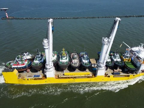 A large vessel with unique lifting capabilities carrying multiple tugboats Stock Photos