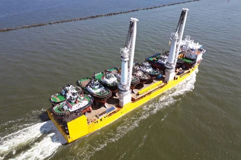 A large vessel with unique lifting capabilities carrying multiple tugboats Stock Photos