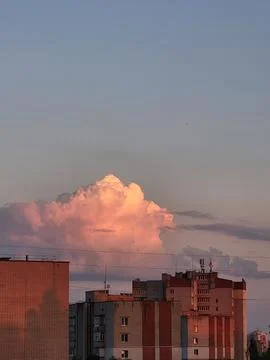Large voluminous cumulus cloud over city buildings at sunset Stock Photos