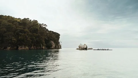 Large waka rowing towards large broken rock Stock Footage 107917226