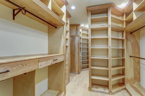 Large walk-in closet lined with built-in drawers, clothes rails and shelving  Stock Photos
