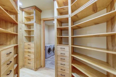 Large walk-in closet lined with built-in drawers, clothes rails and shelving  Stock Photos