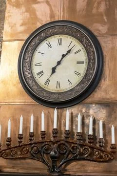 Large wall clock on the fireplace, a candlestick for many candles Stock Photos