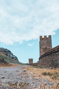 A large wall with a tower against a light blue sky. Stock Photos