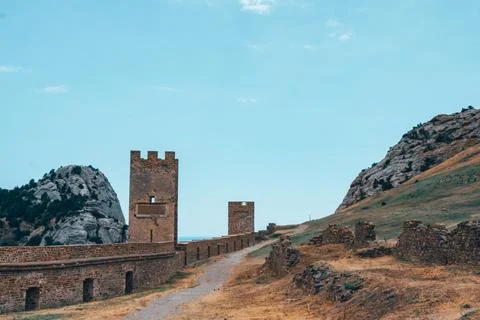 A large wall with a tower against a light blue sky. Stock Photos