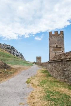 A large wall with a tower against a light blue sky. Stock Photos