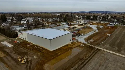 Large Warehouse Construction Project Underway in Suburban Area During Cloud.. Foto stock