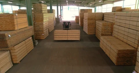 A large warehouse of timber materials. A forklift carries a wooden beam through Видео 106382485