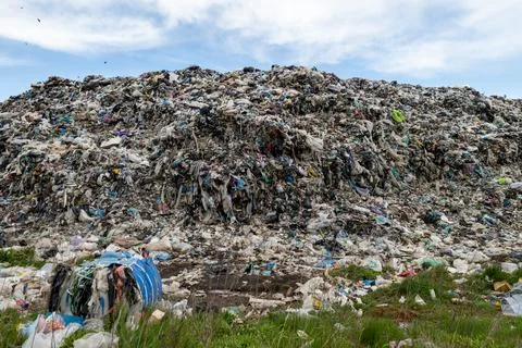 A large waste dump shows a tall heap of trash containing plastic, textiles,.. Stock Photos