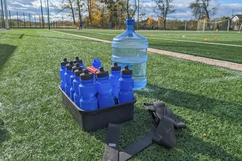 Large water container with bottle container for athletes on football field. Stock Photos