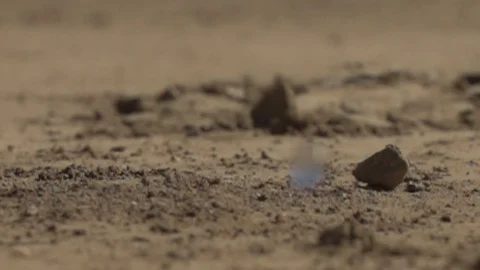 Large water drops impacting dry sandy dirt slpahing up profile Stock Footage 71111804