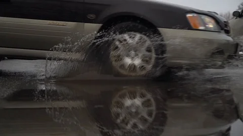 Large water puddle with car driving through and splashing in slow motion. Stock Footage 123640897