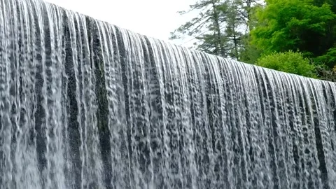 Large Waterfall Cascading down cliff face to fast flowing stream - Slow motion Stock Footage 243770961