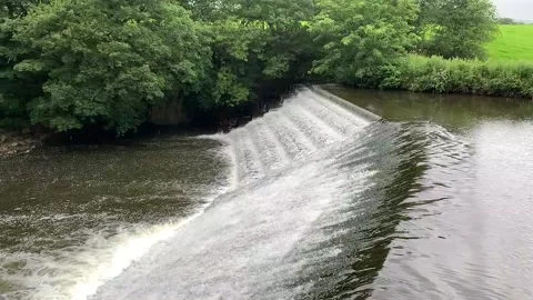Large waterfall with green fields and trees in the background. Stock Footage 136586677