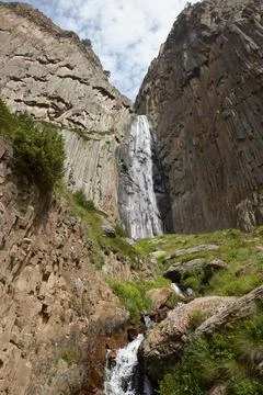 Large waterfall in middle of rocks, high mountains and water flowing among .. Stock Photos