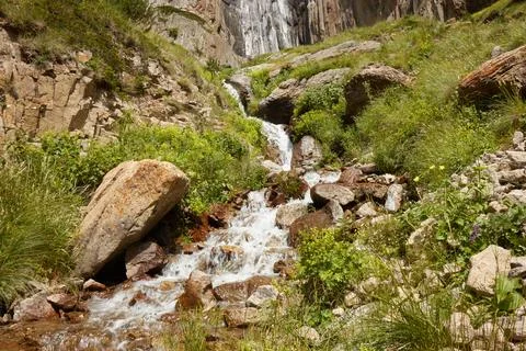 Large waterfall in middle of rocks, high mountains and water flowing among .. Stock Photos