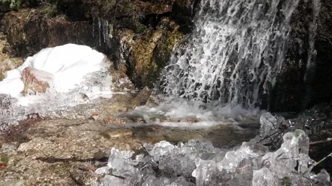 A large waterfall splashes into a pool surrounded by snow and ice in the Valle Stock Footage 293714155