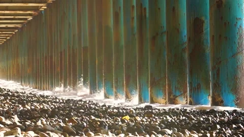 Large wave beats through the columns holding the bridge Video stock 169809894