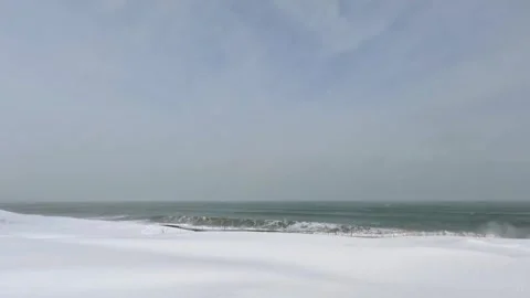 Large wave breaking on snow-covered beach in winter storm Stock Footage 303251976