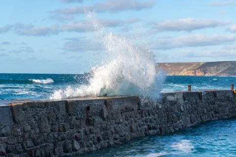 A large wave hitting the harbour wall at Sennen, Cornwall Stock Photos