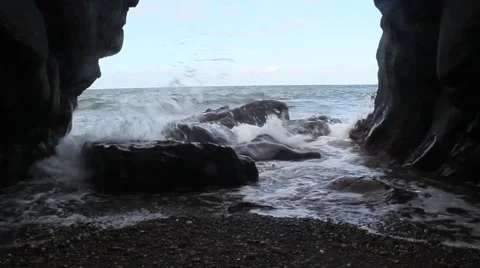 Large waves crash against rock and into cave, clear sky with a few clouds Stock Footage 42743608