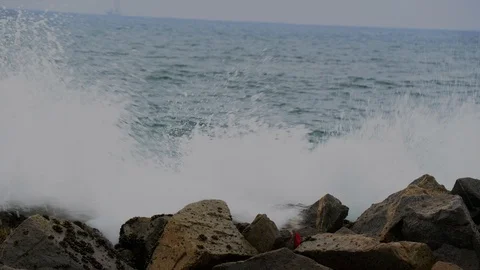 Large waves crash on coastal rocks with boat in the background Stock Footage 112733248