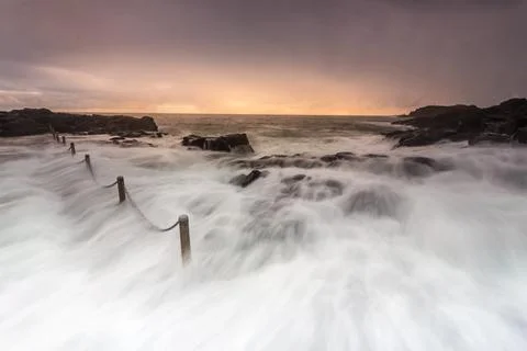 Large waves wash over rocks and into rock pool 스톡 사진