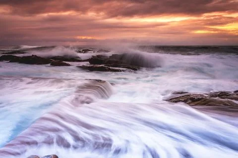 Large waves wash into the tidal ocean pool at sunrise Stock Photos