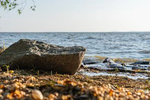 Large weathered granite boulder rests peacefully on the sandy shore beside .. Stock Photos