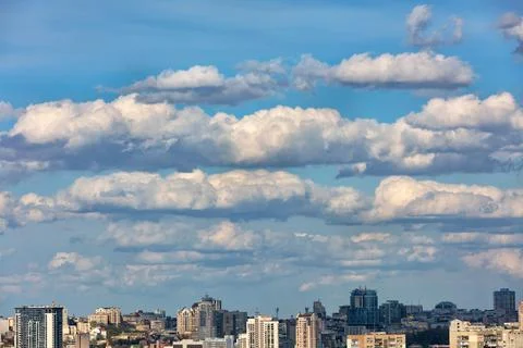 Large white and gray clouds float in the blue sky over the city. Stock Photos