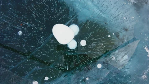Large white bubbles freeze in deep dark blue clear ice. Frozen textures appears Stock Footage 165147138