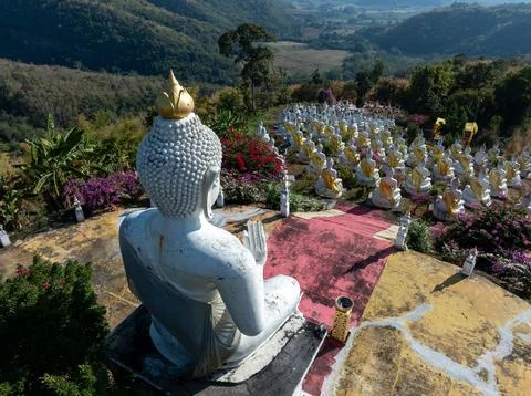 Large White Buddha Statue Overlooking Golden Robed Figures On Hillside In P.. Stock Photos